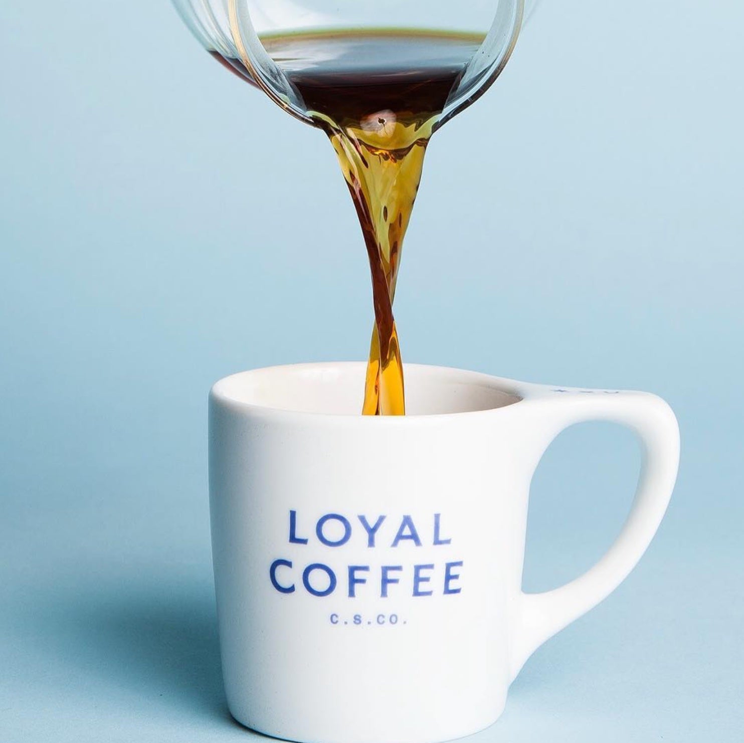 Coffee being poured into a white Loyal Coffee café mug