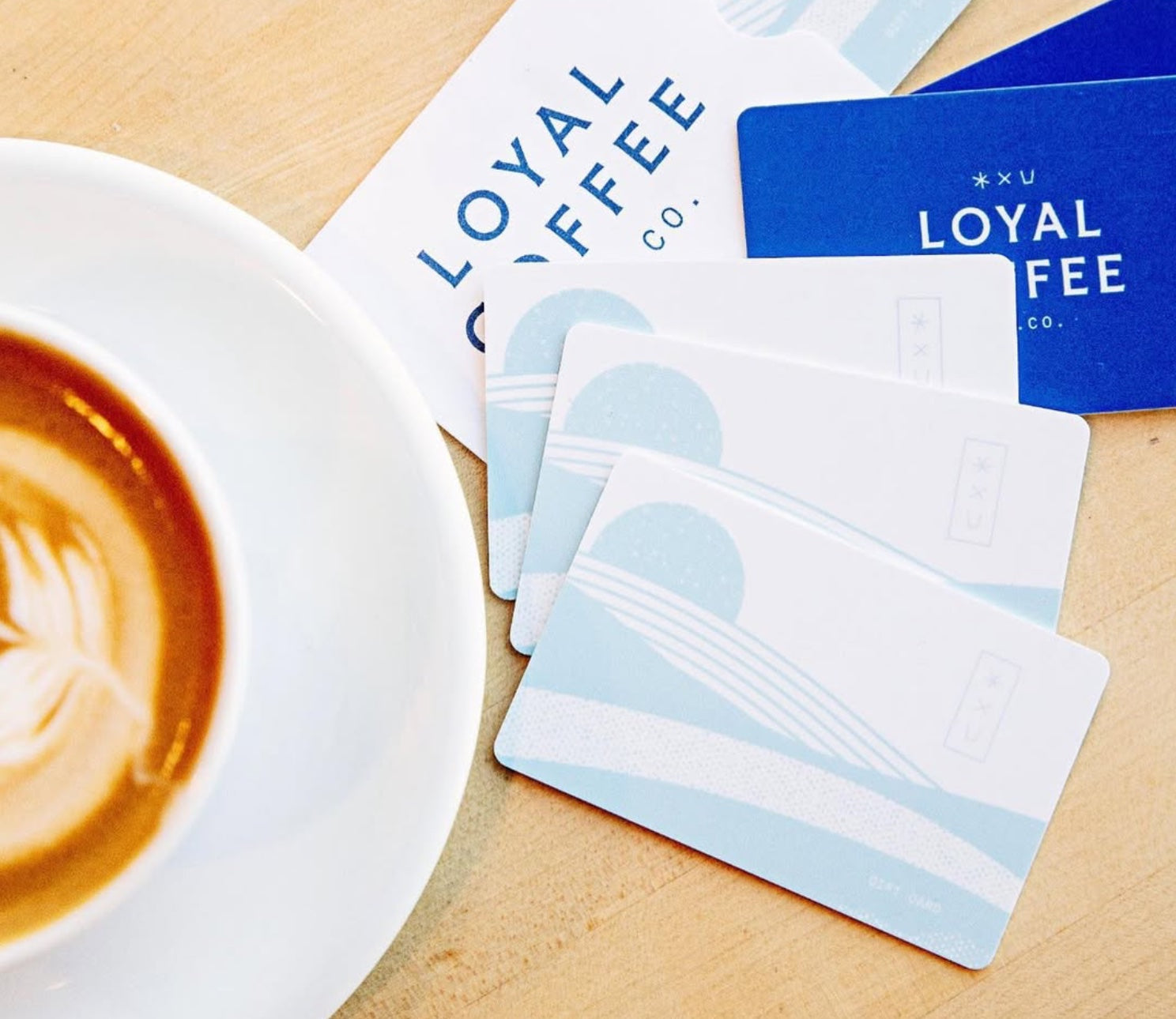Loyal Coffee gift cards beside a cup of coffee